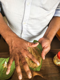 Midsection of man holding hands while sitting on table