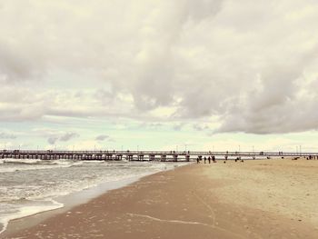 View of calm beach against cloudy sky