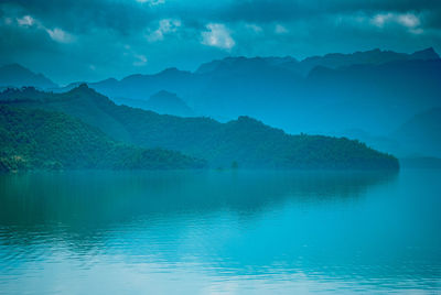 Scenic view of lake by mountains against sky