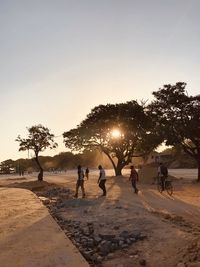 People at beach against sky during sunset