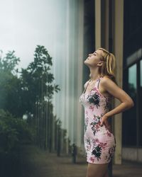 Side view of woman standing against trees against sky