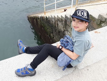 Full length of boy sitting by water