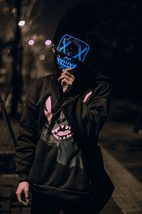 Portrait of the unknown man behind the neon mask at night. dark brown tone