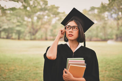 Young woman in graduation gown holding books