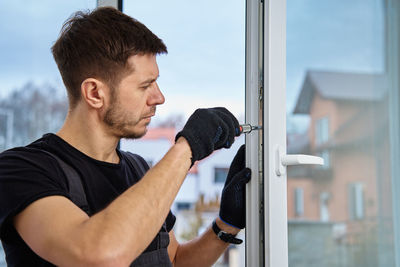 Side view of man looking through window