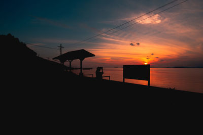 Silhouette beach against sky during sunset