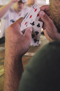 Cropped image of man playing cards at table