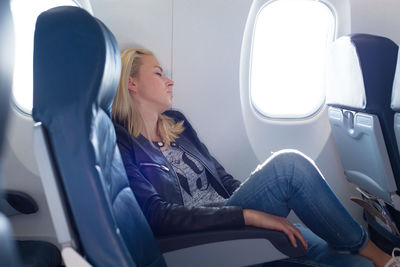 Side view of woman sleeping at airplane