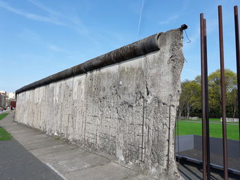 Footpath by wall against sky