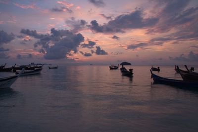 Boats moored in lake against sky during sunset