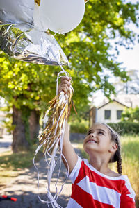 Rear view of smiling woman standing against trees