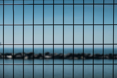 Full frame shot of metal fence against blue sky