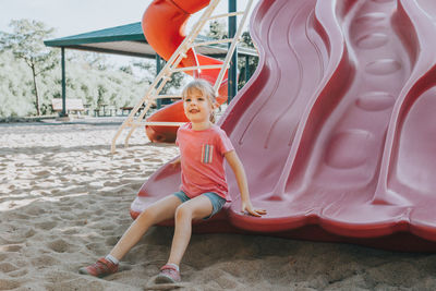 Cute girl sitting on slide in playground