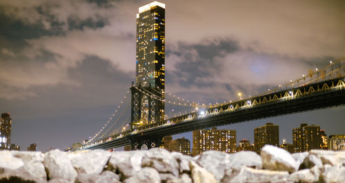 Illuminated bridge over river against sky at night