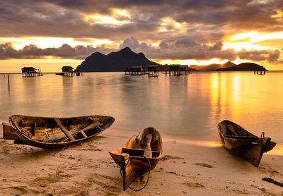 Boats moored on beach against sky during sunset