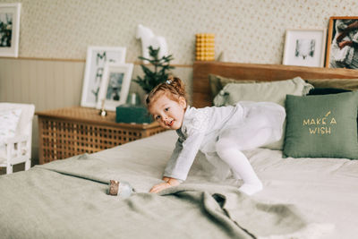 A happy girl is playing on the bed on christmas morning in a room decorated for christmas