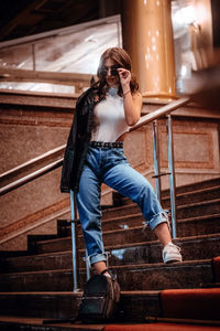 Full length of woman sitting on staircase