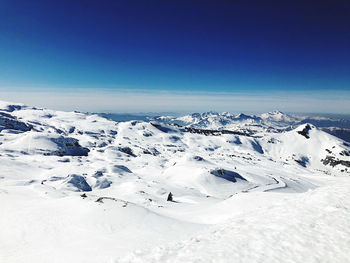 Scenic view of snowcapped mountains against blue sky