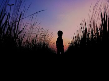 Silhouette man standing on field against sky during sunset