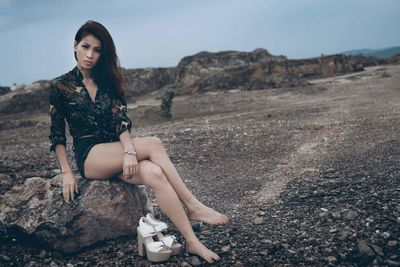 Portrait of beautiful young woman in desert against sky