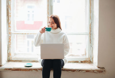 Full length of young woman using mobile phone