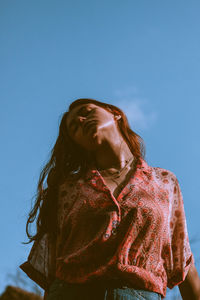 Low angle view of woman standing against blue sky