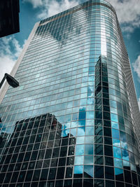 Low angle view of modern glass building against sky