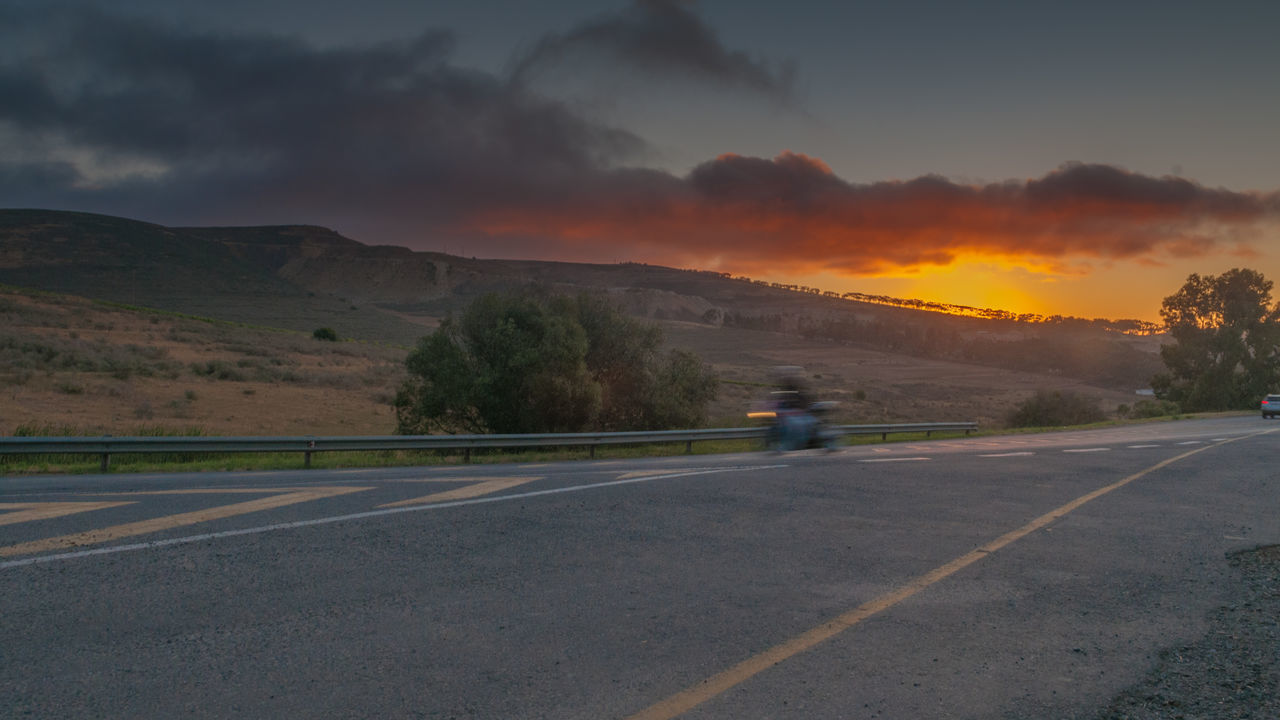 ROAD AMIDST MOUNTAINS AGAINST SKY DURING SUNSET