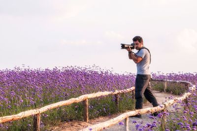 Full length of man photographing on field against sky