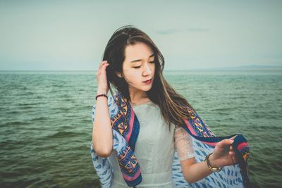 Beautiful young woman looking at sea against sky