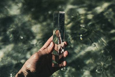 Cropped hand holding crystal over swimming pool