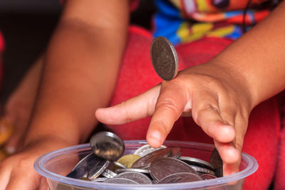 Cropped image of person putting coins into container