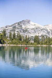 Retired woman paddling packraft on remote wilderness lake.