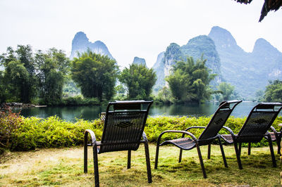 Chairs on table by lake against mountains