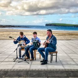 Men playing guitar on beach