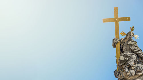 Low angle view of cross sculpture against sky