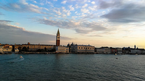 View of buildings at waterfront against cloudy sky