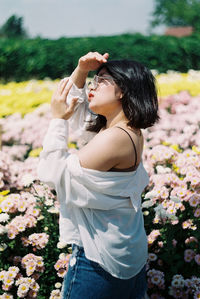 Side view of woman standing by flowering plants