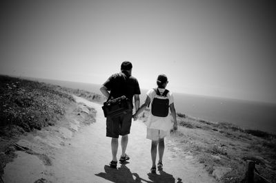 Rear view of people walking on beach