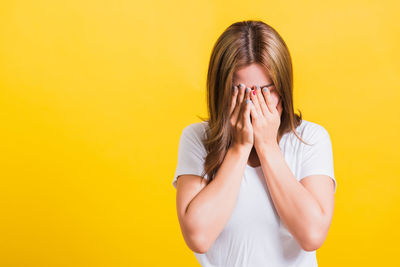 Young woman wearing mask against yellow background