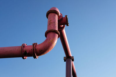 Low angle view of pipe against clear blue sky