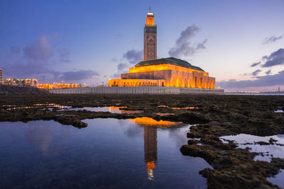 Buildings by sea against sky during sunset