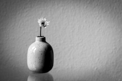 Close-up of white flower vase on table against wall