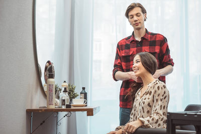 Stylist barber styling long hair for beautiful asian young woman in beauty salon, working moment