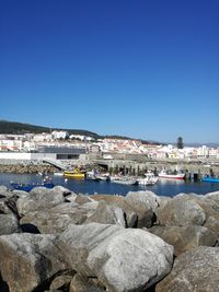 Scenic view of sea by buildings against clear blue sky