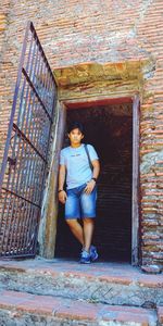 Full length portrait of man standing at door of historic building