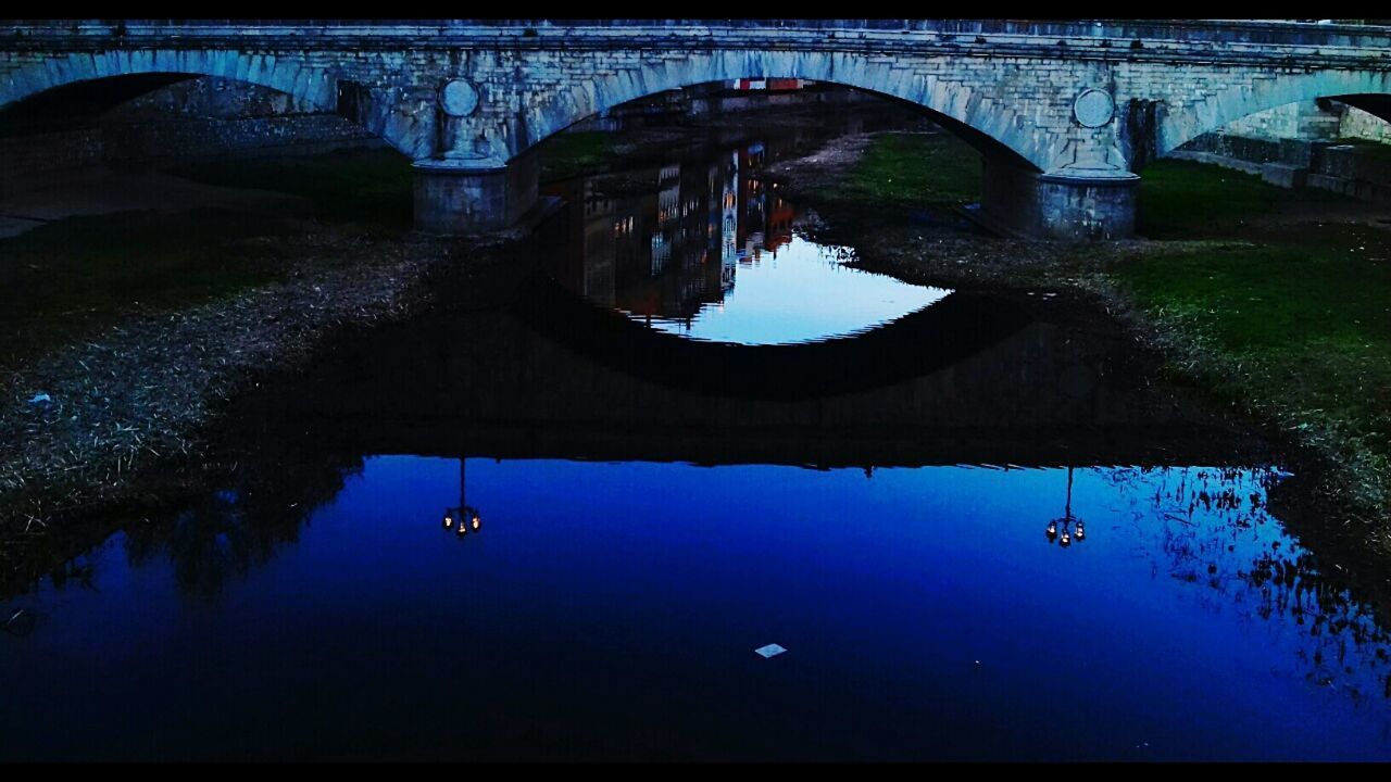 REFLECTION OF ARCH BRIDGE OVER RIVER AGAINST SKY