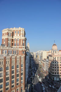 Buildings in city against clear blue sky