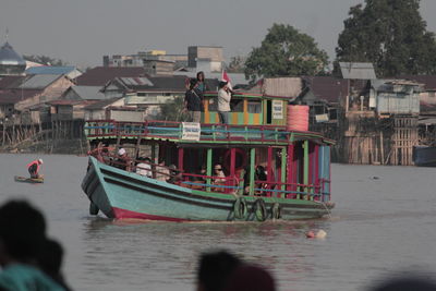 Boats in river against buildings in city