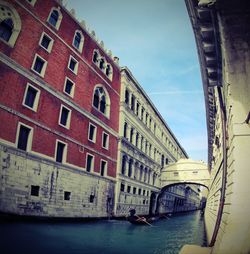 Canal amidst buildings in city against sky